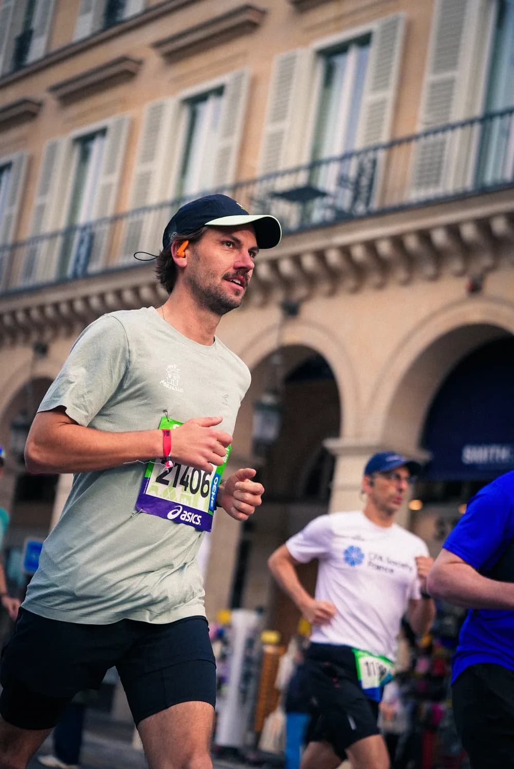 Un coureur dossard au ventre, en pleine course dans une rue parisienne