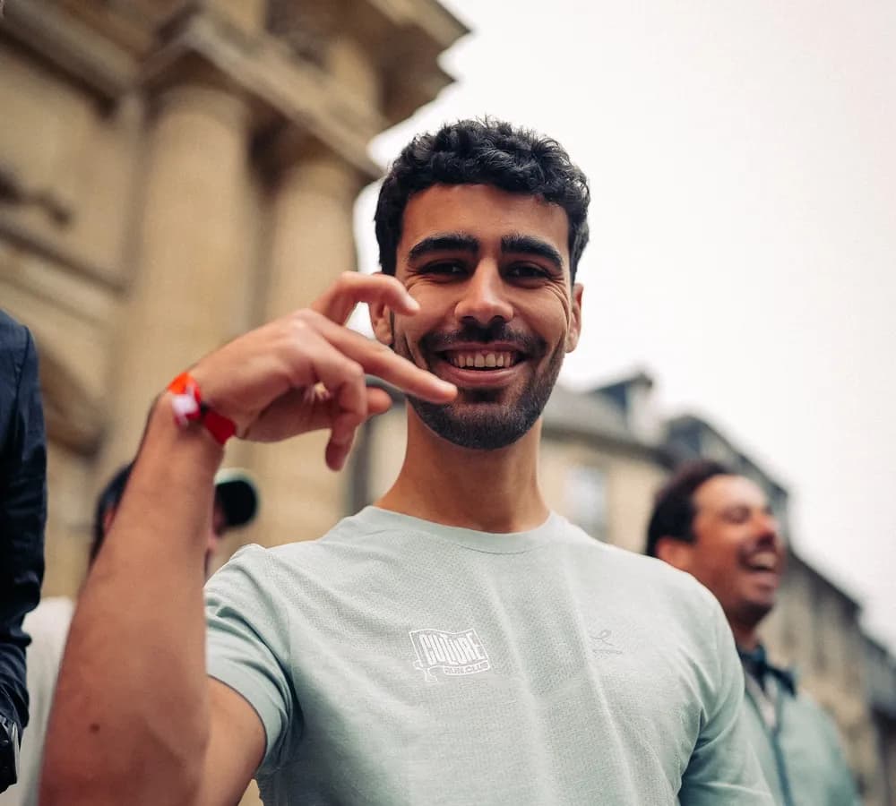 Un coureur salue l’objectif au milieu de son crew